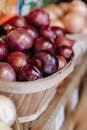 Basket of fresh red onions on a wooden stall, perfect for market or farm stock photos.